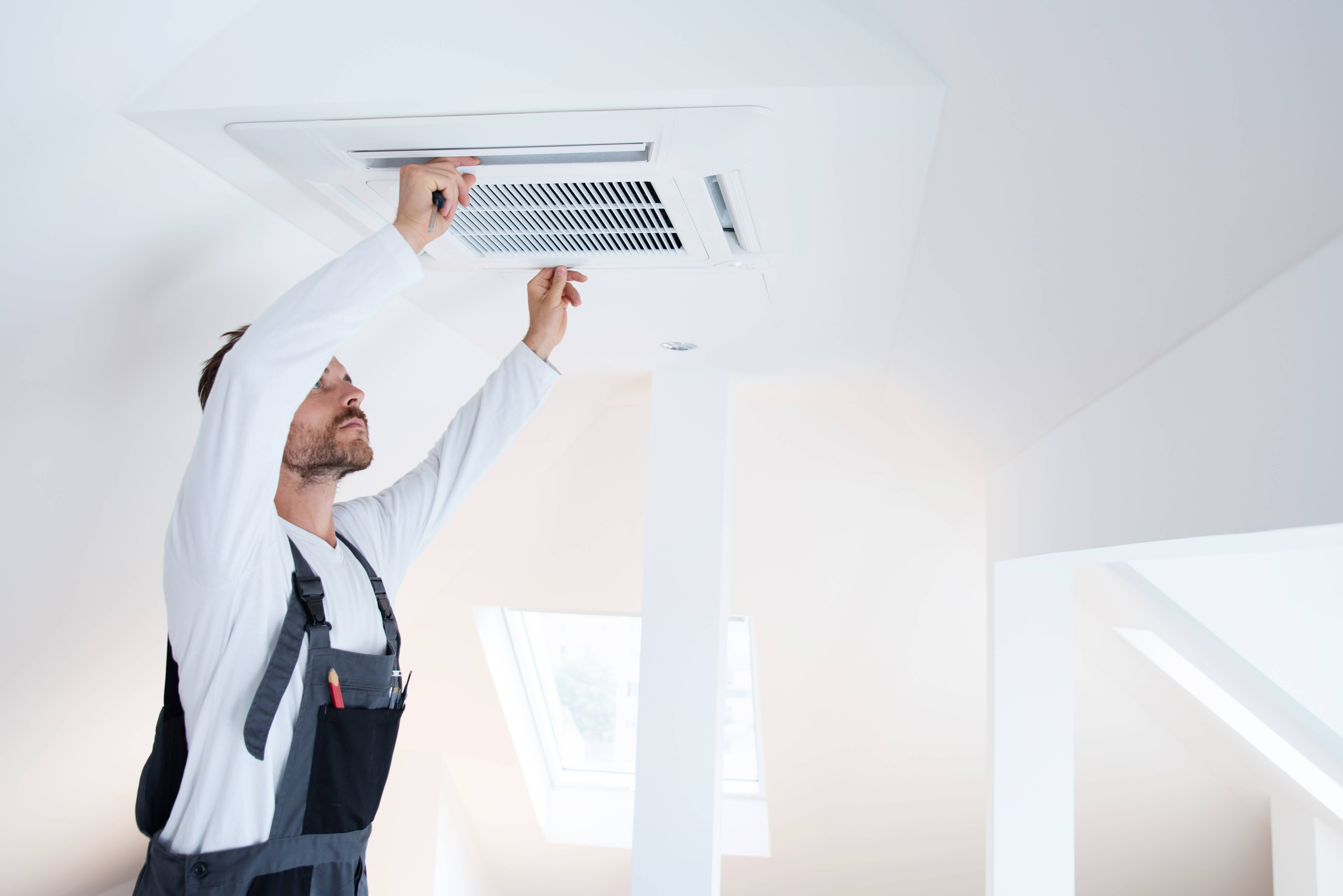 Ein Handwerker installiert in einem Passivhaus eine Lüftungsanlage