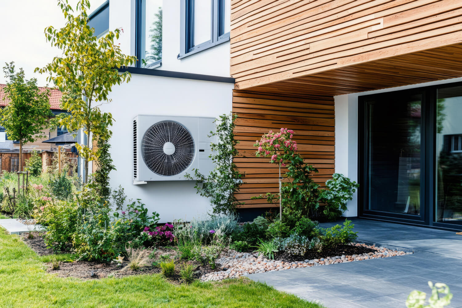 Wärmepumpe an Wand montiert im Garten eines modernen Hauses