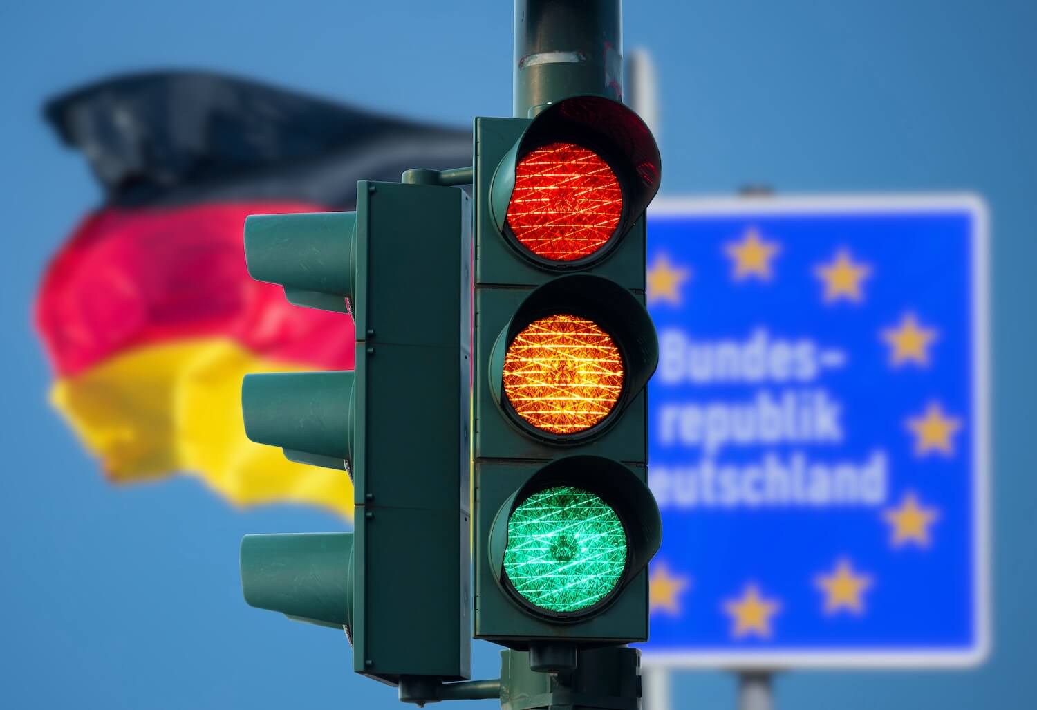 Eine Ampel vor unscharfer deutscher Flagge und EU-Schild symbolisiert das Ende der Ampel-Koalition in Deutschland.