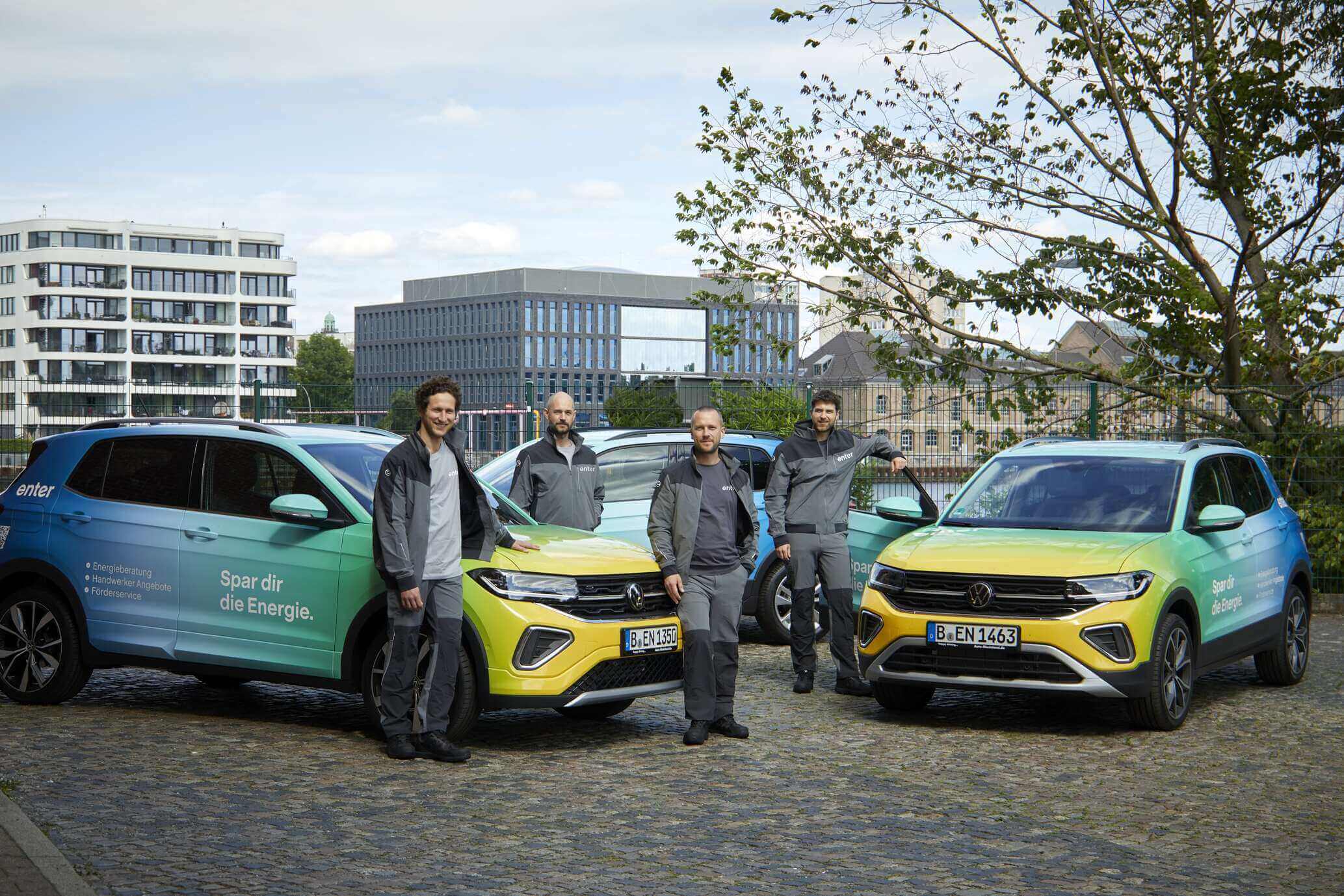 Enter Energieberater-Team vor Firmenwagen in einem klimaneutralen Quartier mit modernen Wohngebäuden