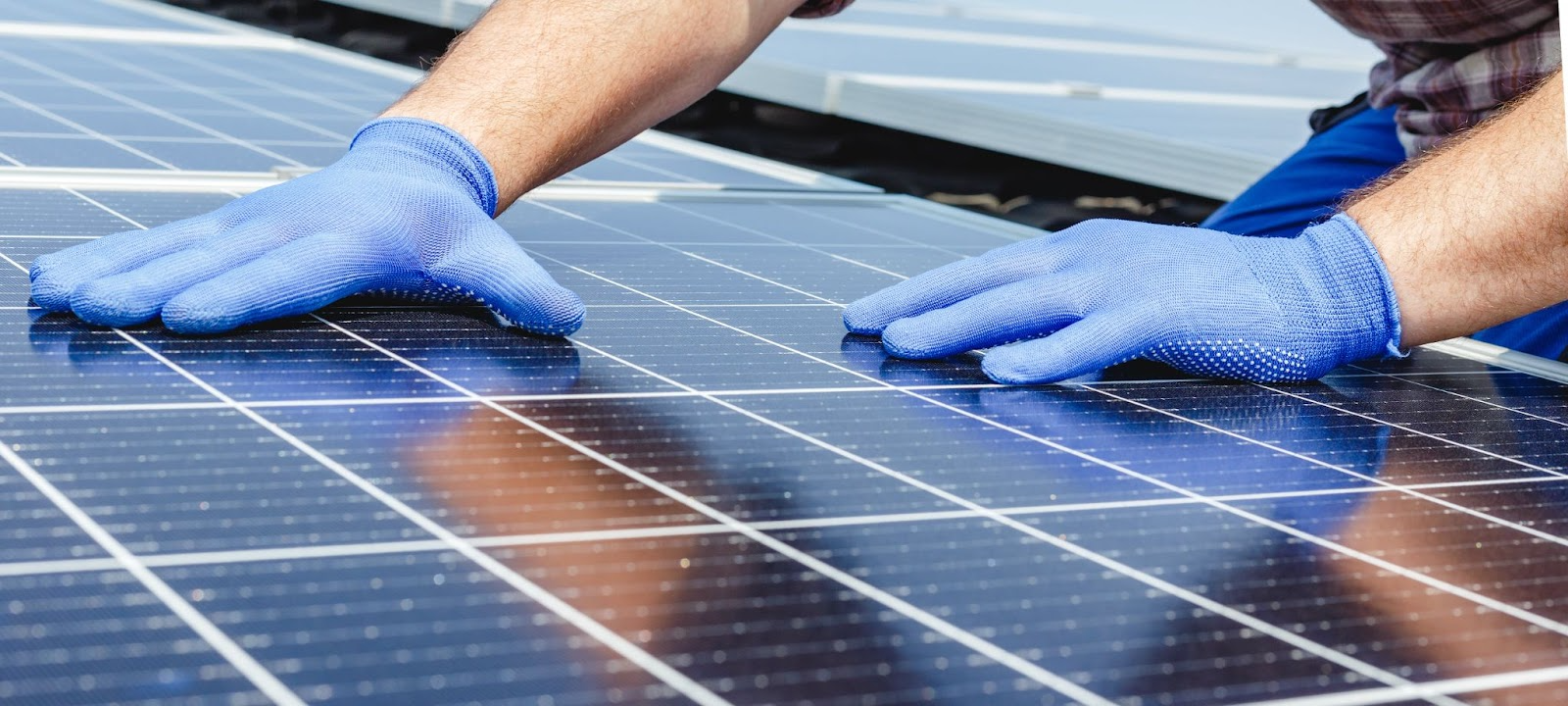 Handwerker installiert Solarmodule auf Dach aufgrund der Solarpflicht Deutschland fĂĽr Neubauten