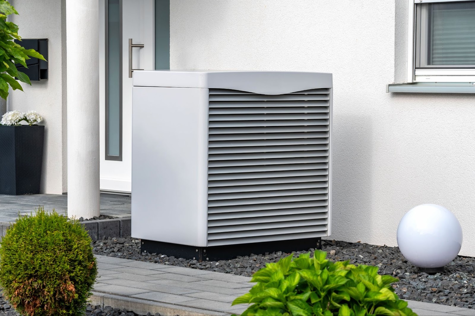 Monoblock vs Split Wärmepumpe Vergleich - kompakte Außeneinheit mit Lamellengitter vor Hauswand