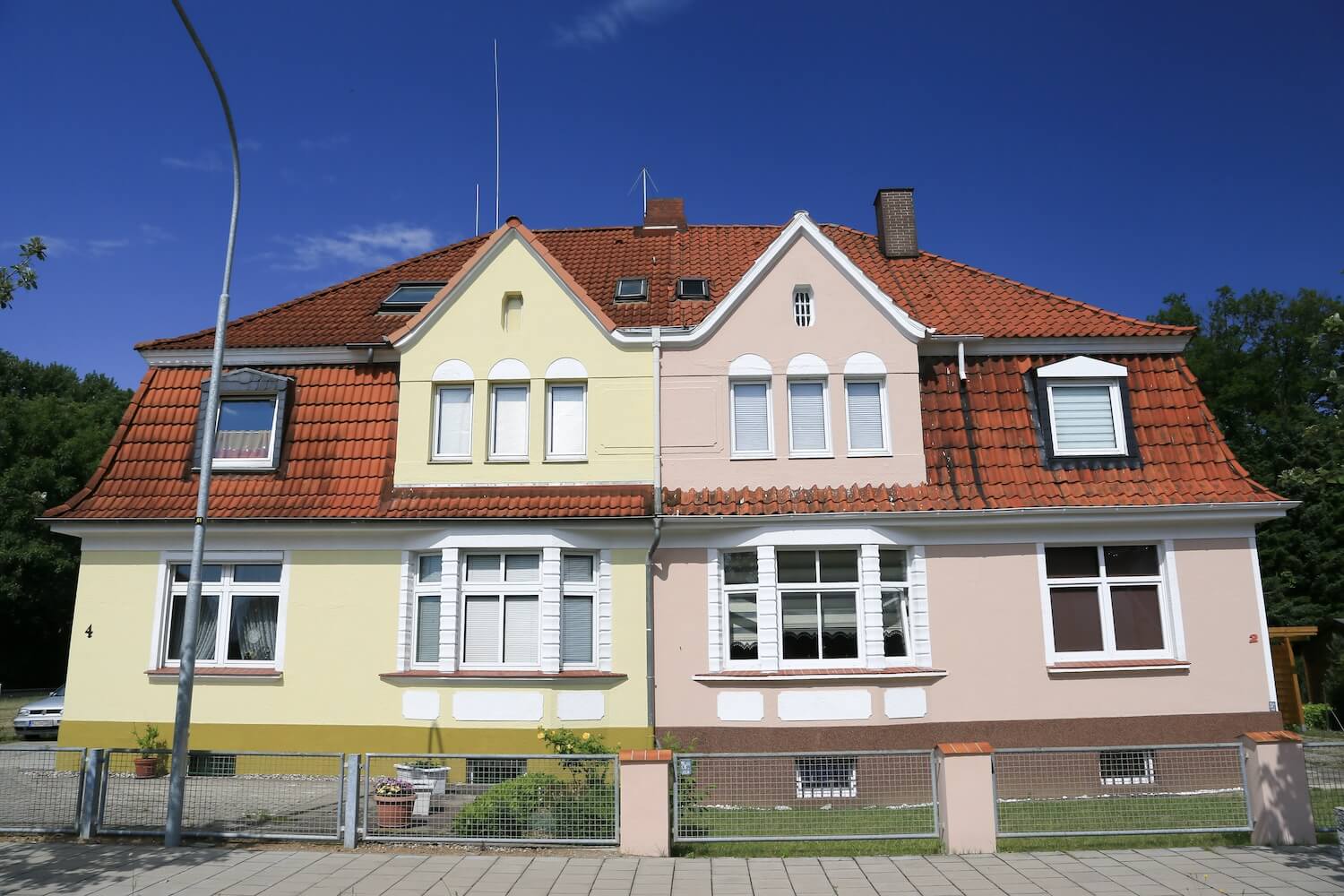 Zwei sanierte Doppelhaushälften mit neuer Dämmung, frischer Fassade und modernen Fenstern – Beispiel für energetische Sanierung einer Doppelhaushälfte im Altbau.