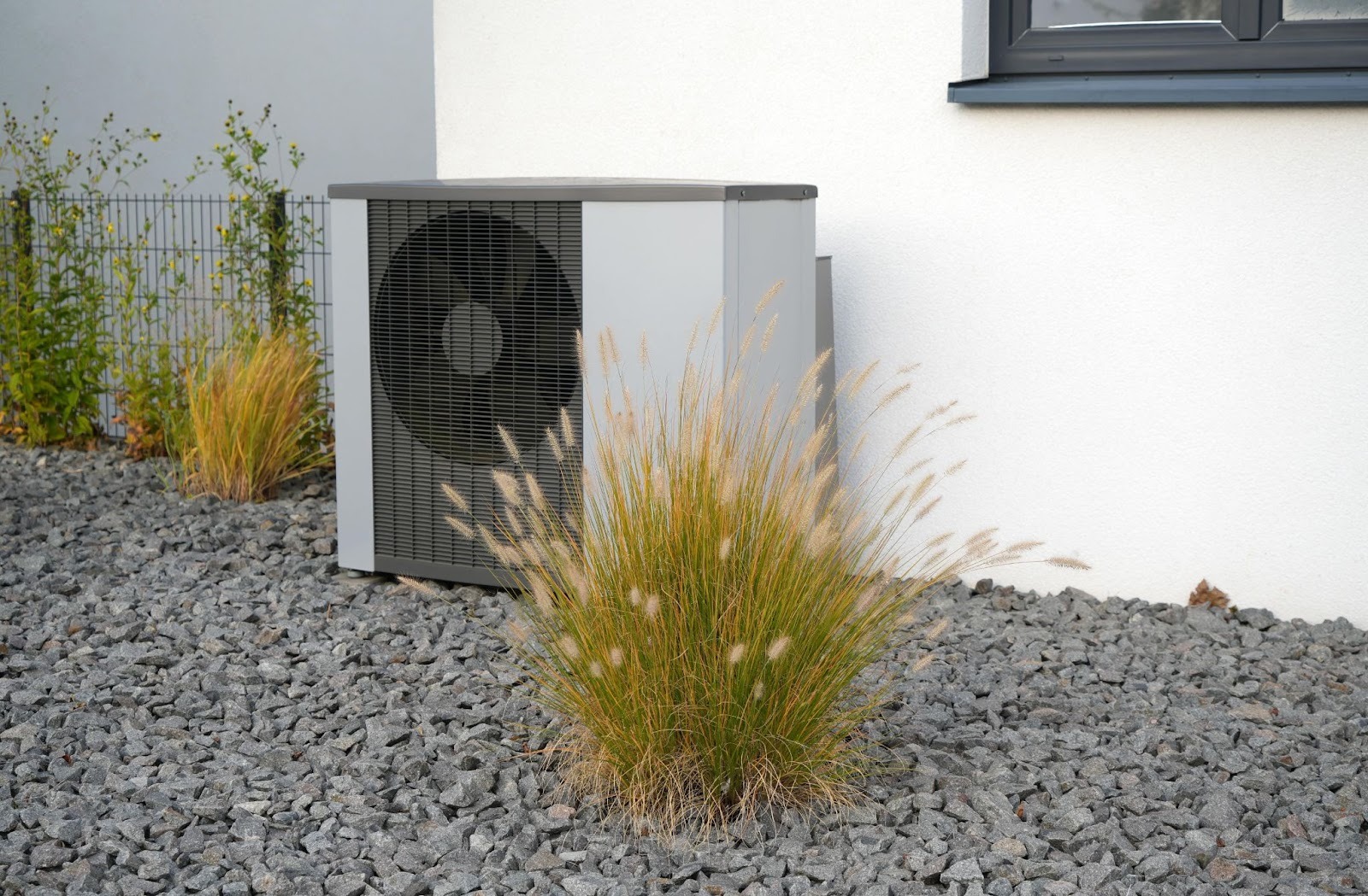 Moderne, reversible Wärmepumpe steht vor einem Einfamilienhaus. 