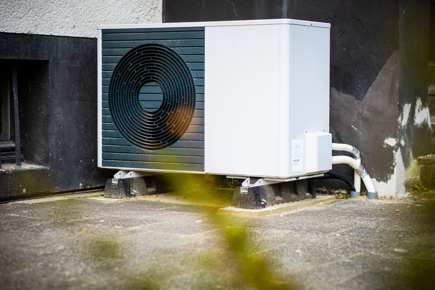 Außeneinheit eine Wärmepumpe mit Betonfundament auf zwei Sockeln stehend