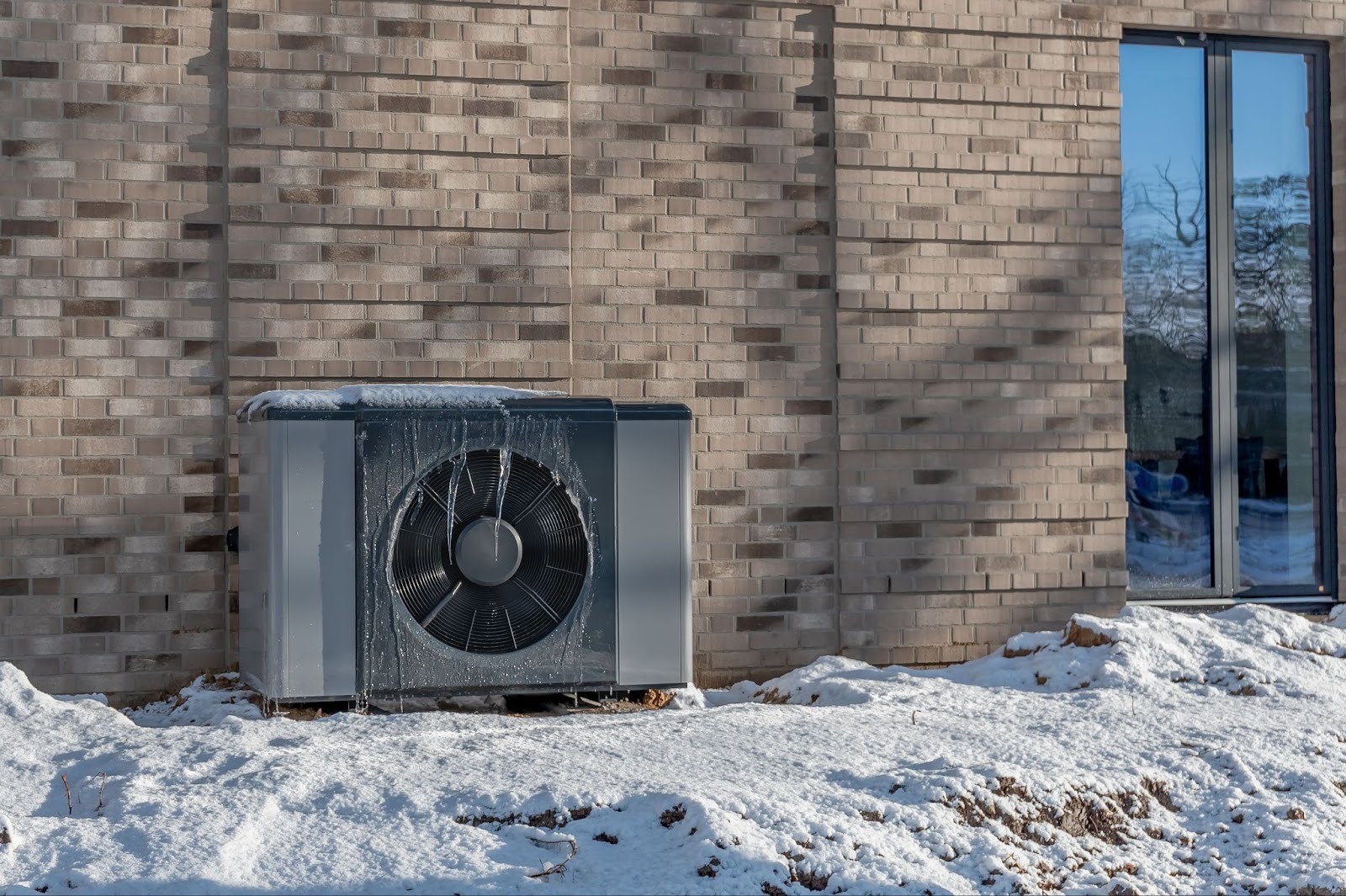 Eine eingefrorene Wärmepumpe vor einem Haus. 