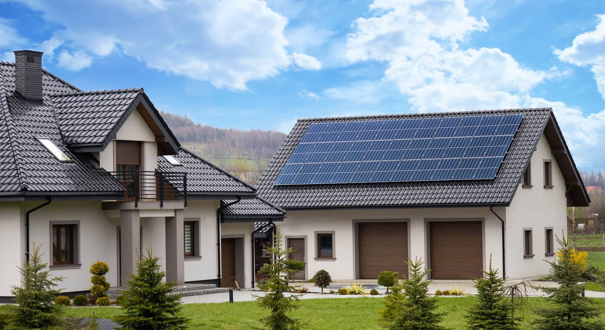 WohnhĂ€user im GrĂŒnen, von denen eines mit Solarpaneelen ausgestattet ist.