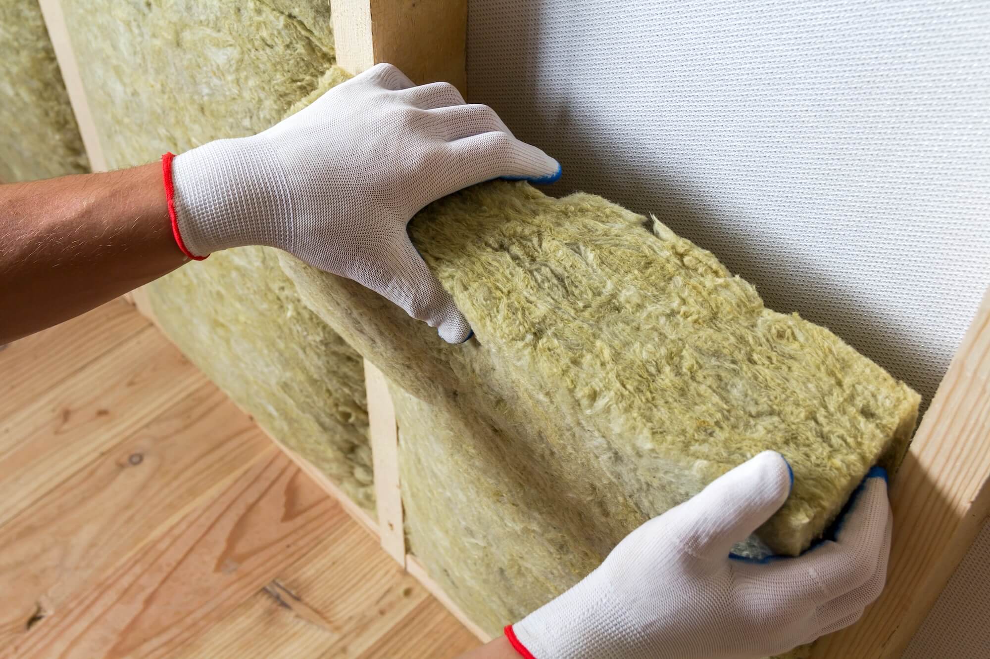 Handwerker dämmt eine Wand um den Stromverbrauch der Wärmepumpe zu senken