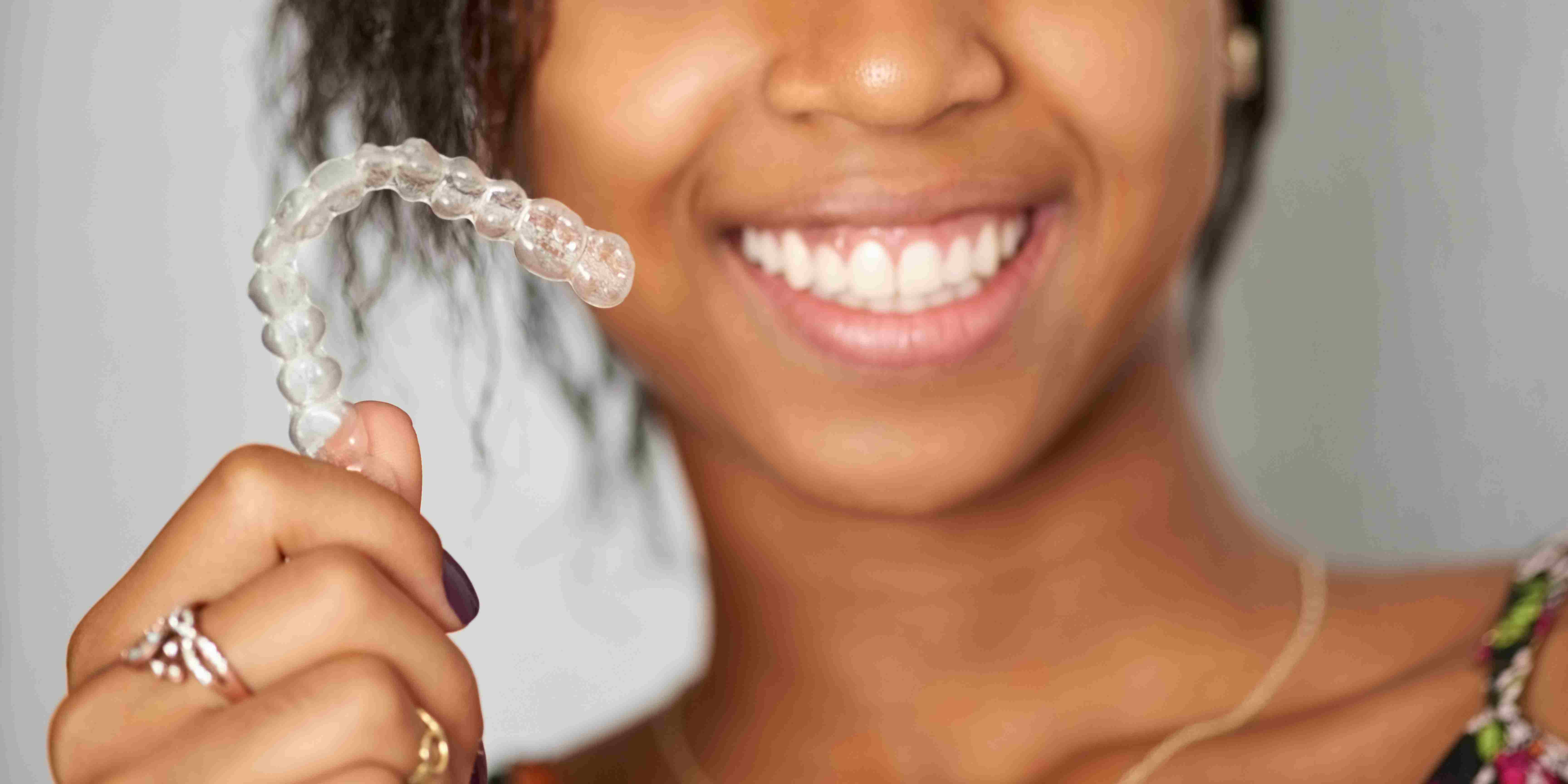 Patient smiling with clear Invisalign aligners to correct crowded teeth, gaps, and bite issues at W Plus Dental in Washington, DC.