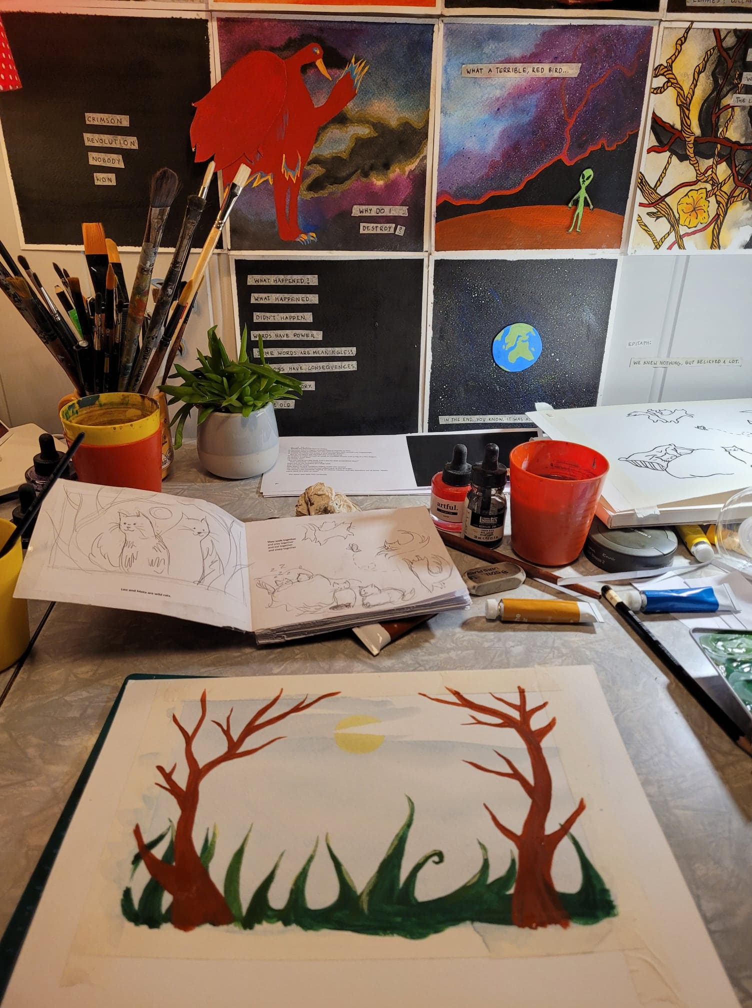 A messy workspace, with an in-prgress painting in the foreground