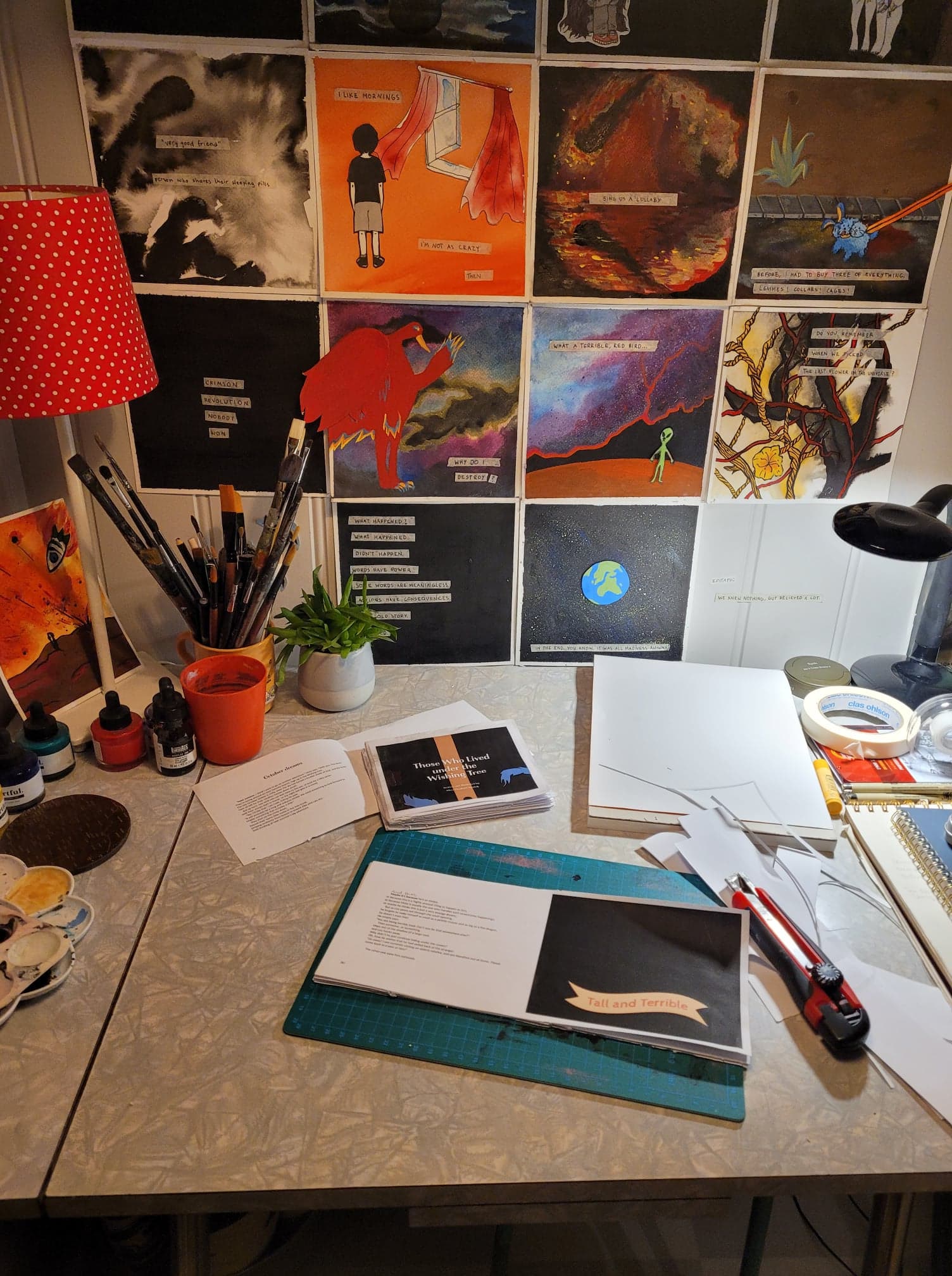 A messy workspace, with an in-project paper cutting project, soon-to-be children's book in the foreground