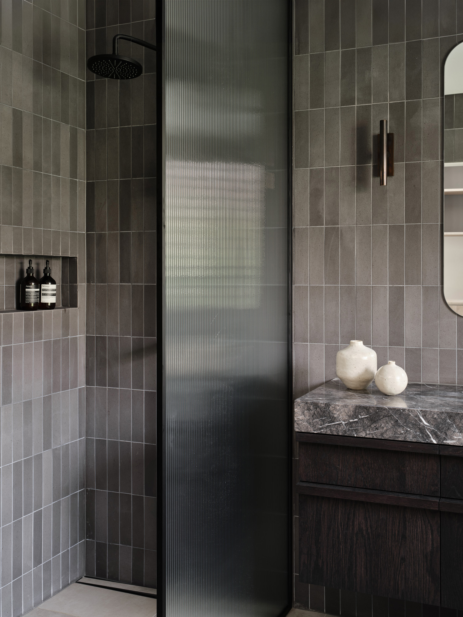Spacious shower with fluted glass wall and overhead shower head 
