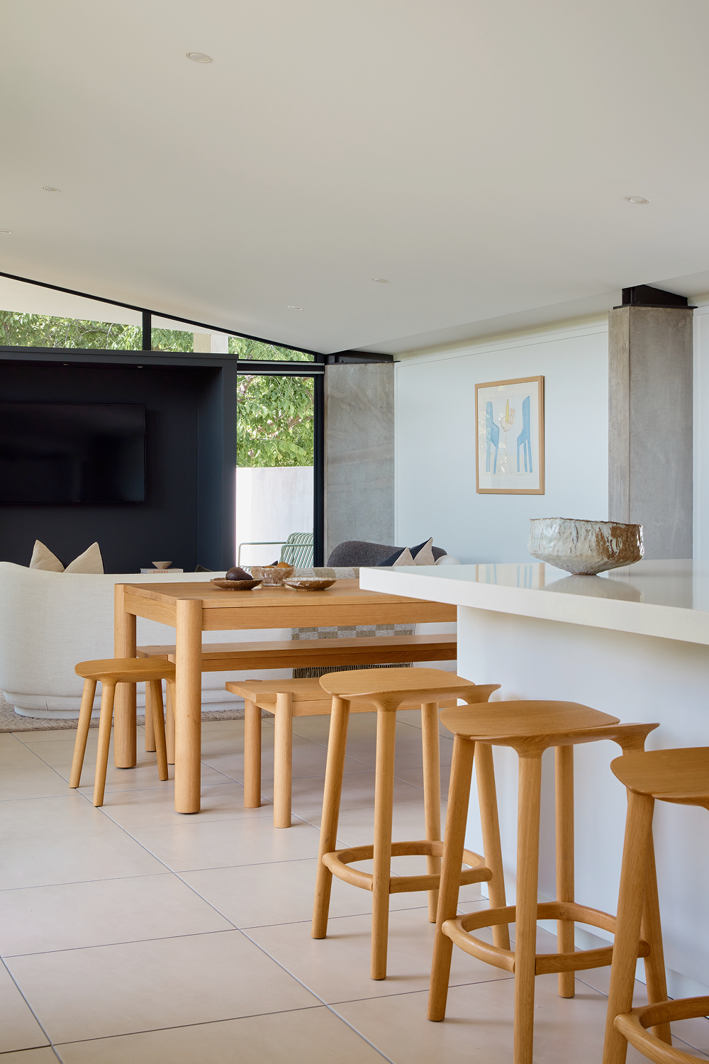Oak stools and dining table beside white kitchen island and living area