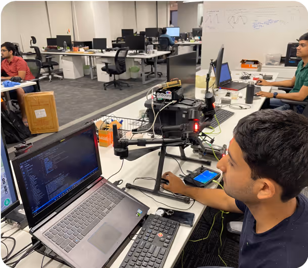 Man controls drone with laptop & phone.