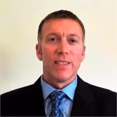 Man in suit, smiling slightly.