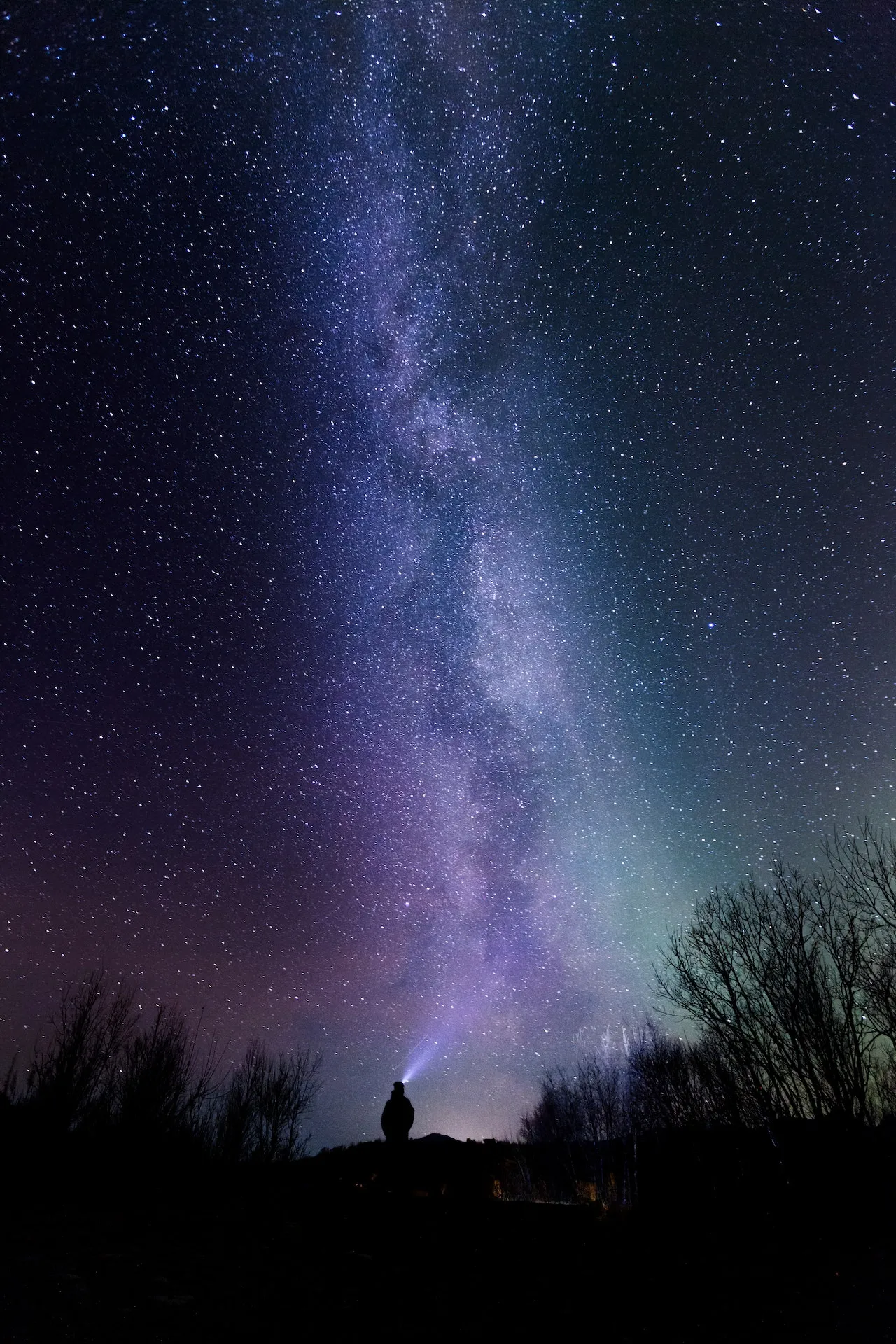 A man looking up at the sky at night in purple and blue