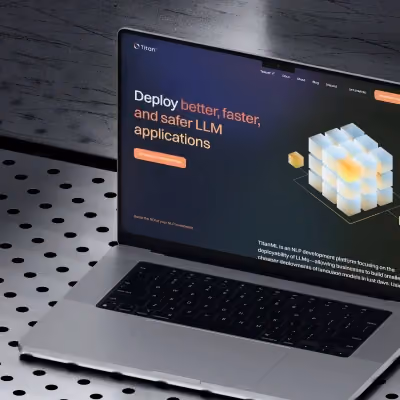 TitanML website on laptop screen showcasing LLM deployment platform with 3D cube visual.