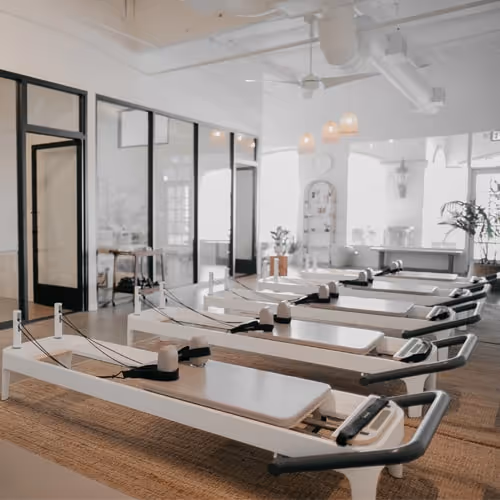 Reformer Pilates studio with multiple reformer machines lined up, airy natural light interior — perfect for group reformer classes in [City].