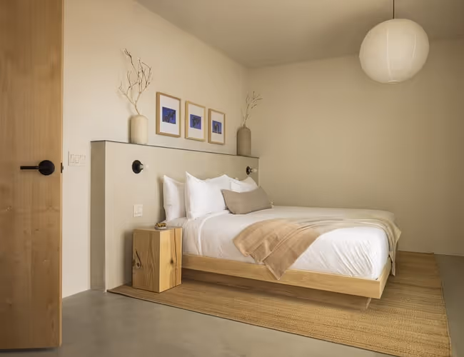 Minimalist bedroom with wooden furniture, neutral tones, modern lighting, and natural decor creating a warm, relaxing atmosphere.