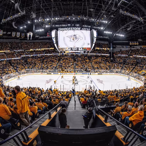 Packed Bridgestone Arena in Nashville during an ice hockey game, with fans wearing yellow cheering for the Nashville Predators.