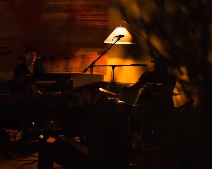 Musicians playing a late-night jam session under warm lamp light, with instruments and microphones creating a relaxed lounge atmosphere.