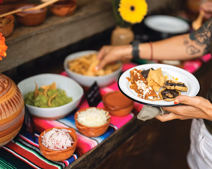 Traditional Mexican brunch with chilaquiles, tortilla chips, guacamole, cheese, and salsa served on a colorful table setup.