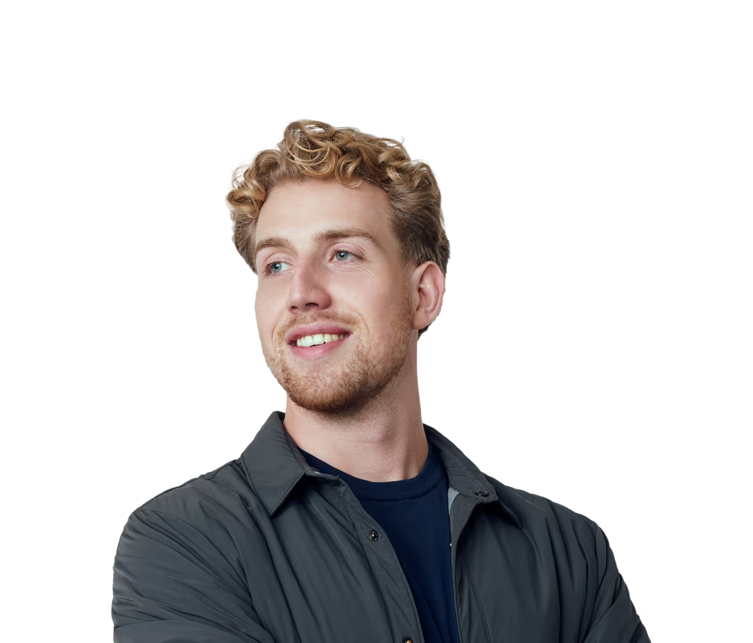 Jonge man met krullend blond haar en baard draagt een donkergrijze jas en kijkt glimlachend naar rechts met gekruiste armen.