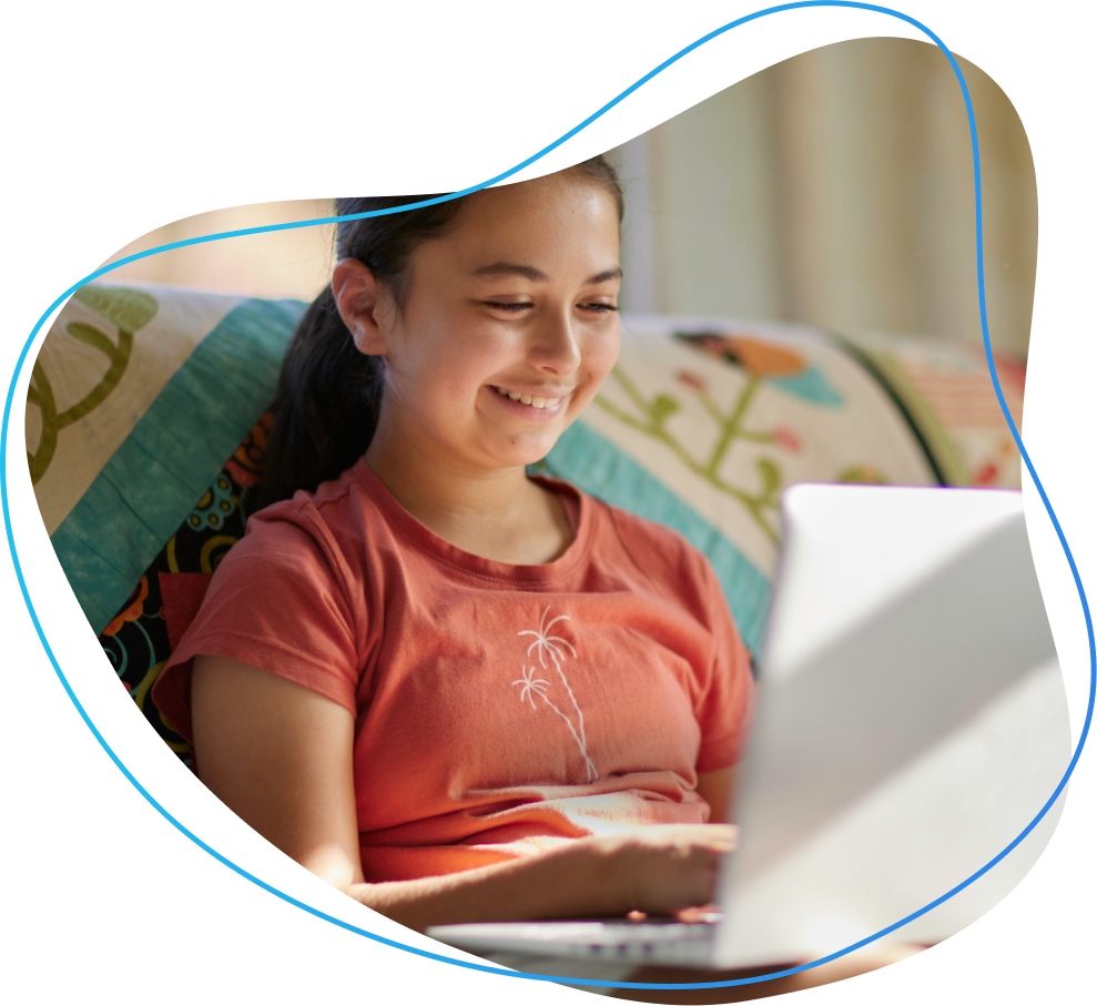 A young Māori boy, on his bed smiling and playing on a tablet device