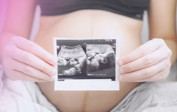 Ung gravid kvinne viser stolt bilde av ultralyd