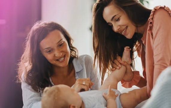 Two women cuddling with their baby