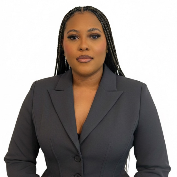 Portrait of a woman with long braided hair wearing a black blazer against a white background.