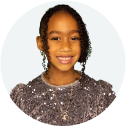 Smiling young girl with curly hair wearing a sparkly gray top and a necklace.