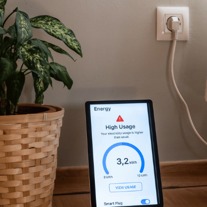 Tablet displaying a high electricity usage alert from a smart plug, indicating excessive energy consumption in a home setting, with a plant in a wicker basket nearby