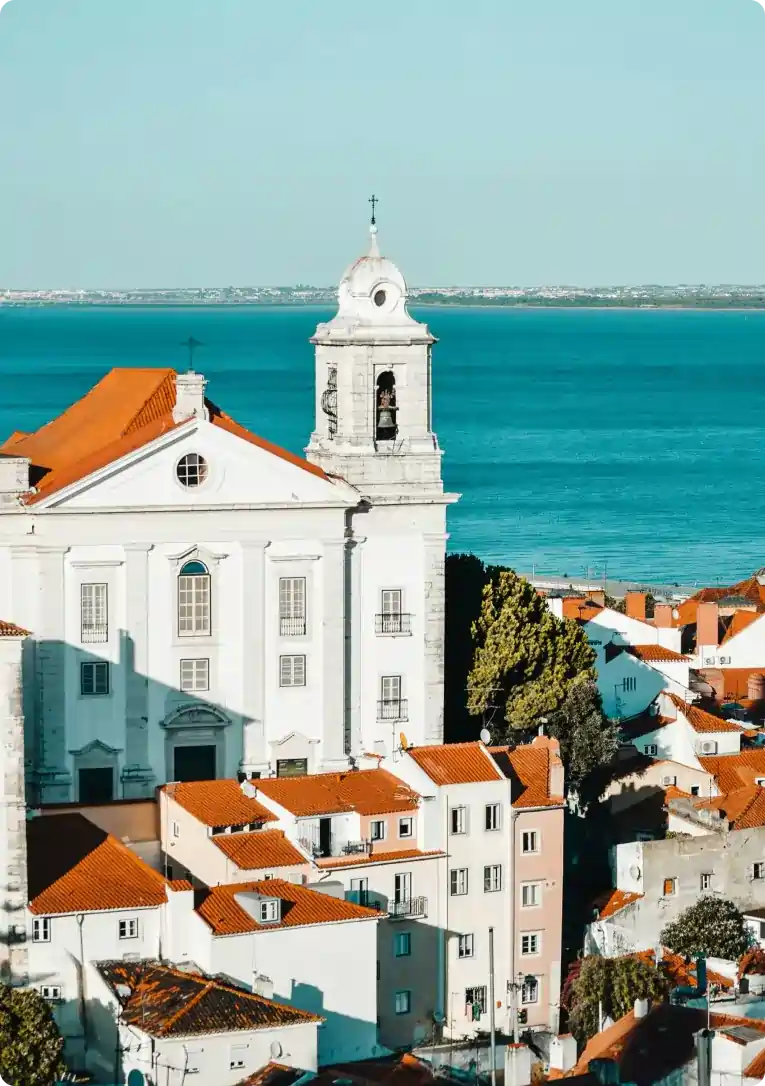 Lisbon's coastal view and church architecture highlighting Airbnb management in Portugal.