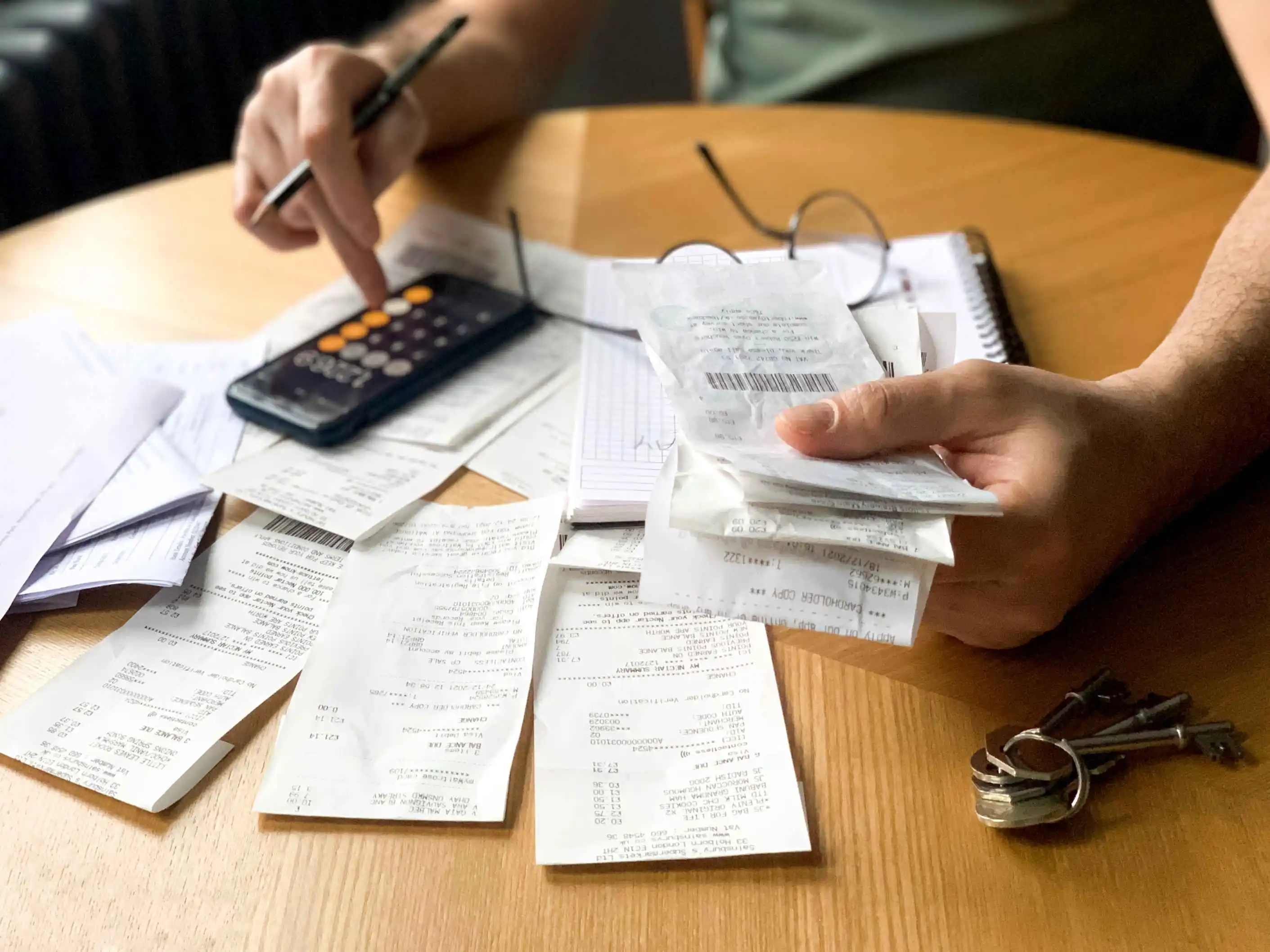 Flat lay of various business expense receipts, a calculator, and a spreadsheet, representing allowable expenses for rental income.