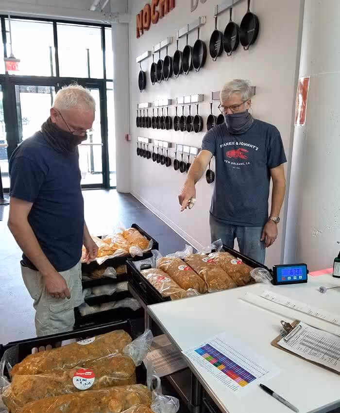 Two grey haired men looking at packages of food while wearing masks indoors