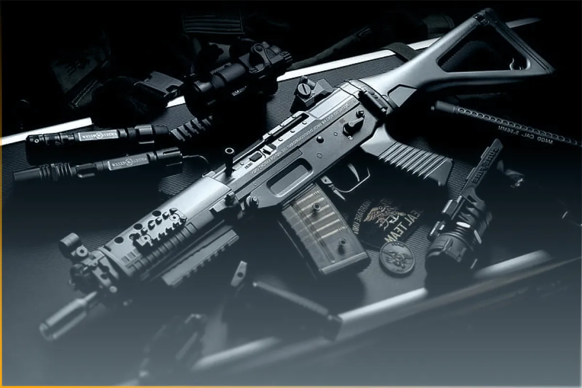Tactical assault rifle with accessories like scope, flashlight, and magazines on a black case.