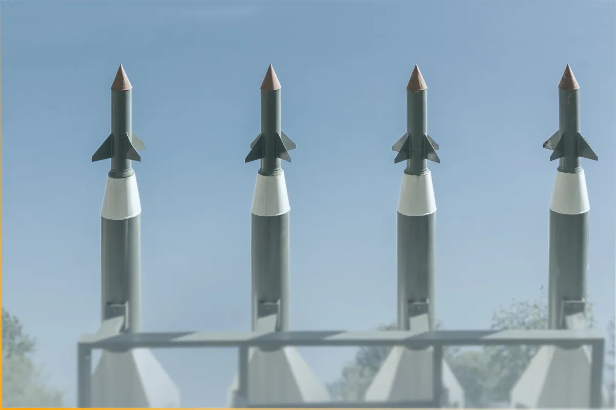 Four air defense missiles aligned upright against a clear blue sky background.