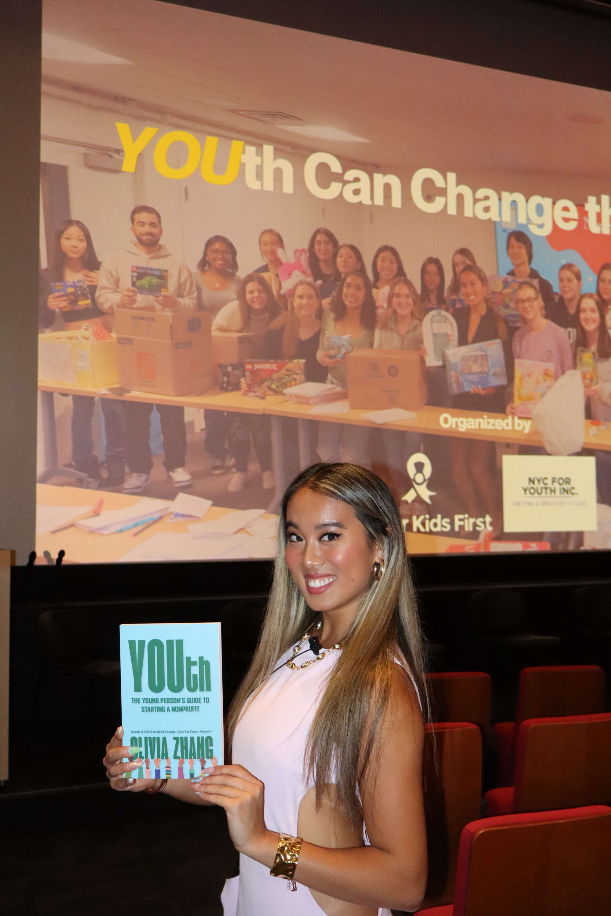Olivia holding her own book, YOUth, at Cancer Kids First very first YOUth Can Change the World Conference in New York City