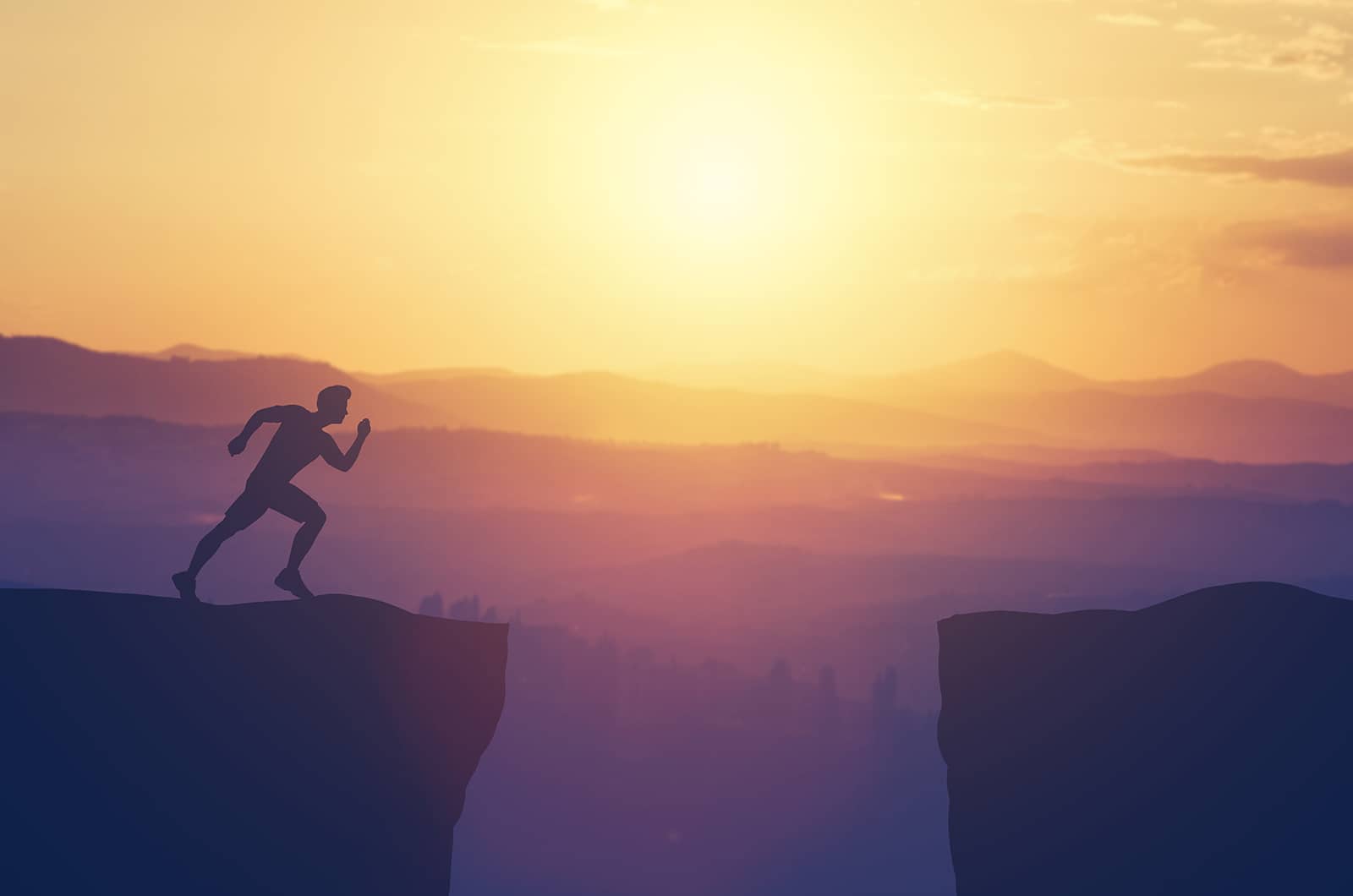 A man jumping over a gap in a mountain