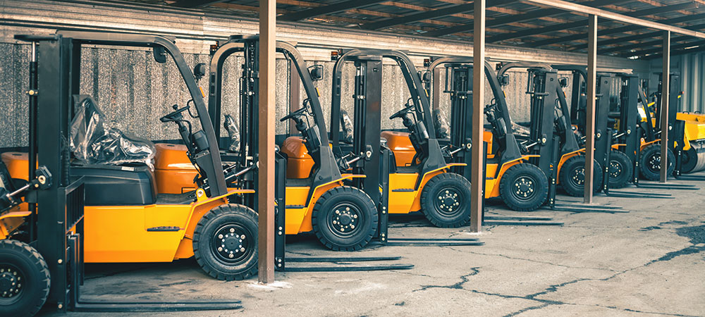 A row of yellow forklifts parked up in a line