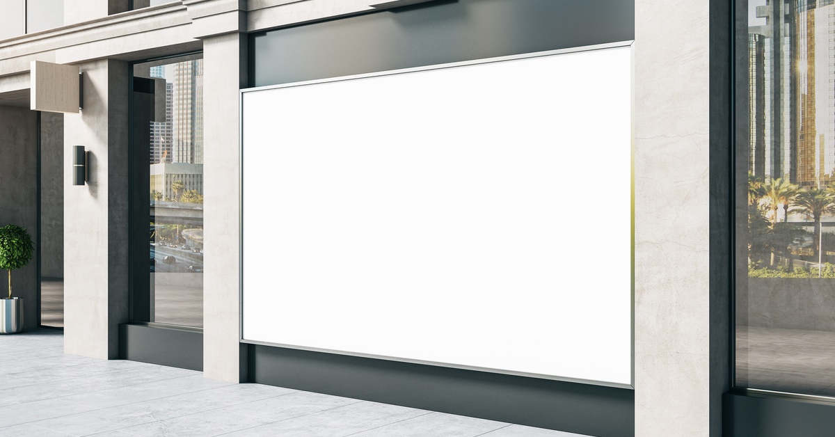 The exterior of a building with stone columns and a large, blank, white banner filling an advertisement space.