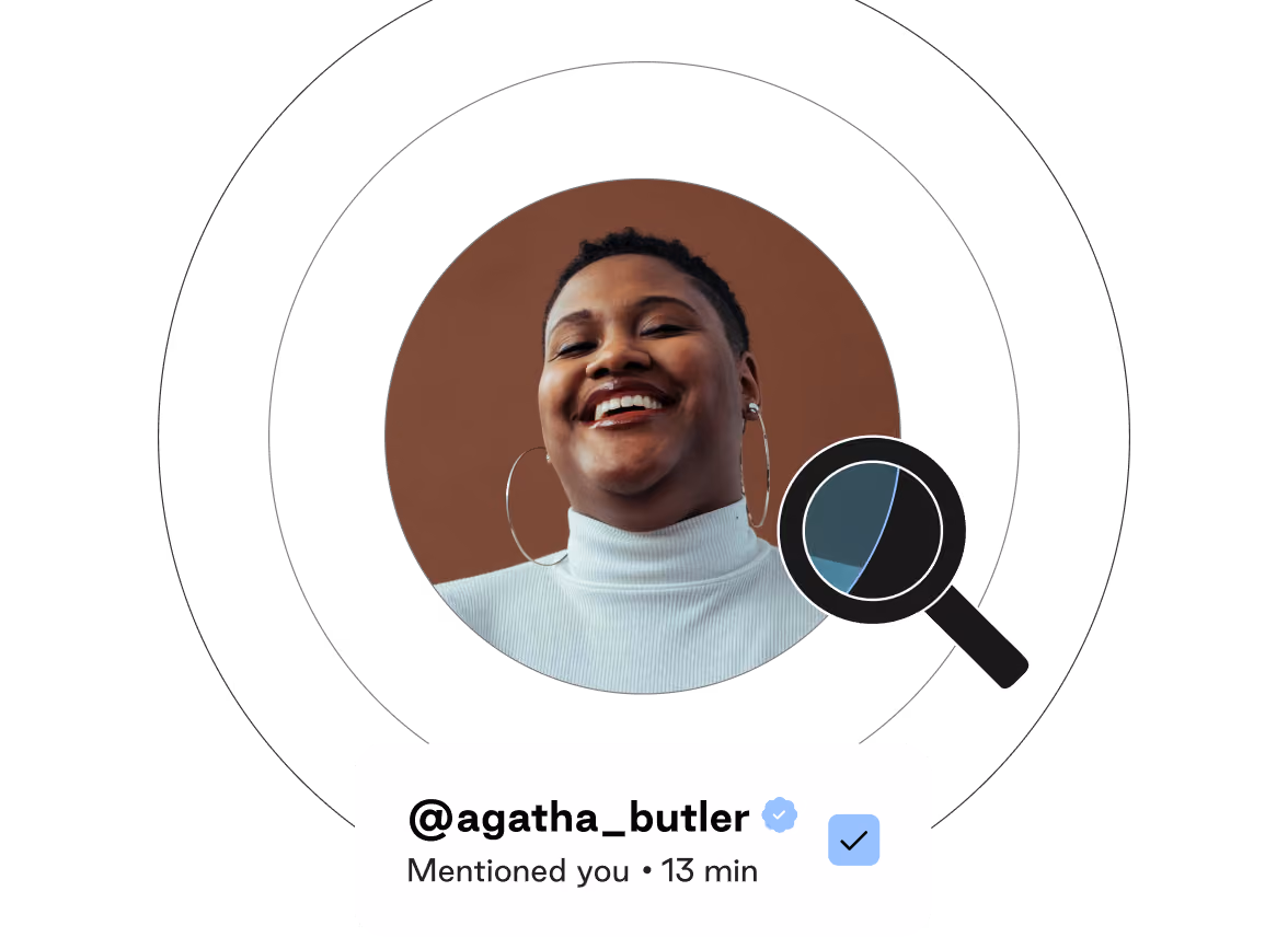 Smiling woman with short hair and large hoop earrings wearing a white turtleneck, inside a circular frame with a magnifying glass icon, below a notification showing the username @agatha_butler with a verification checkmark and 'Mentioned you • 13 min' text.