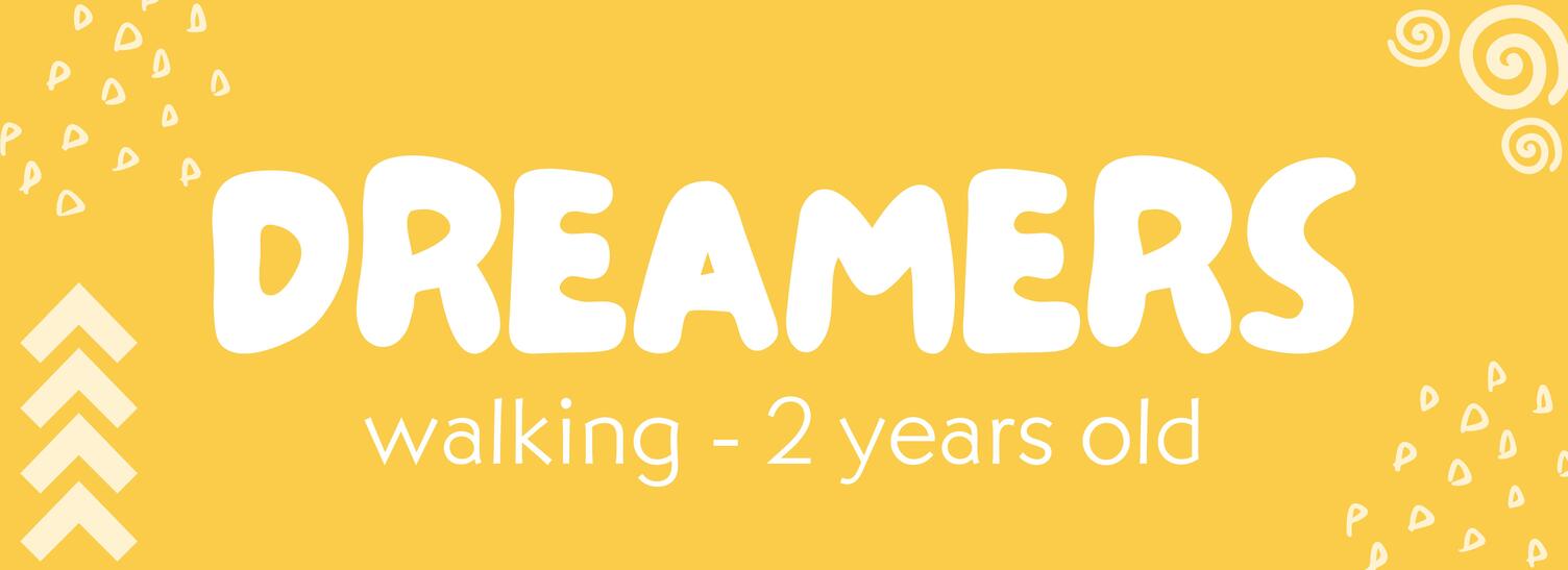 A woman in a doorway holding 2 kids in her arm as another woman behind a counter smiles at her.