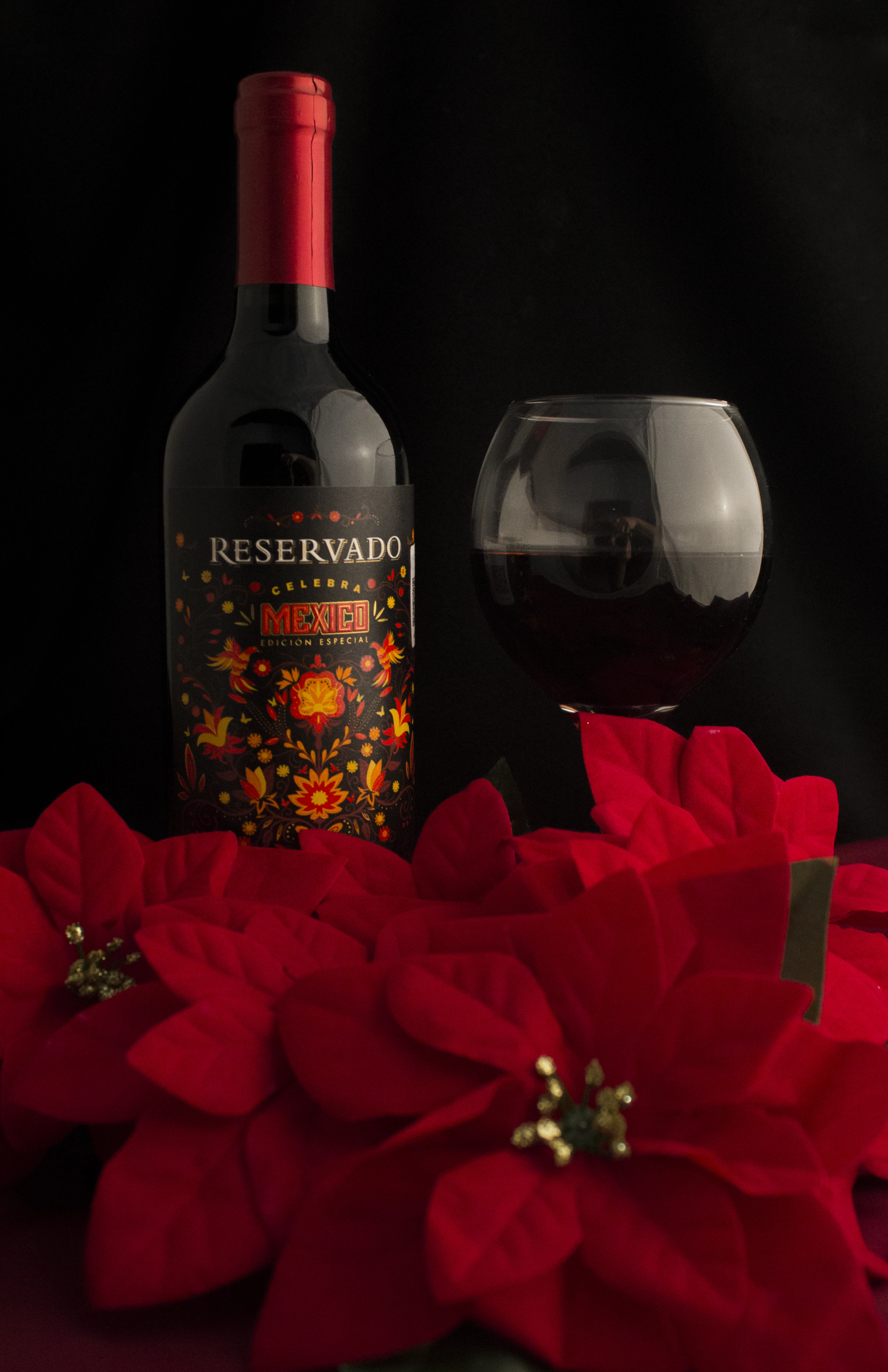 Botella de vino con flores de nochebuena en escenario para fotografía de producto.