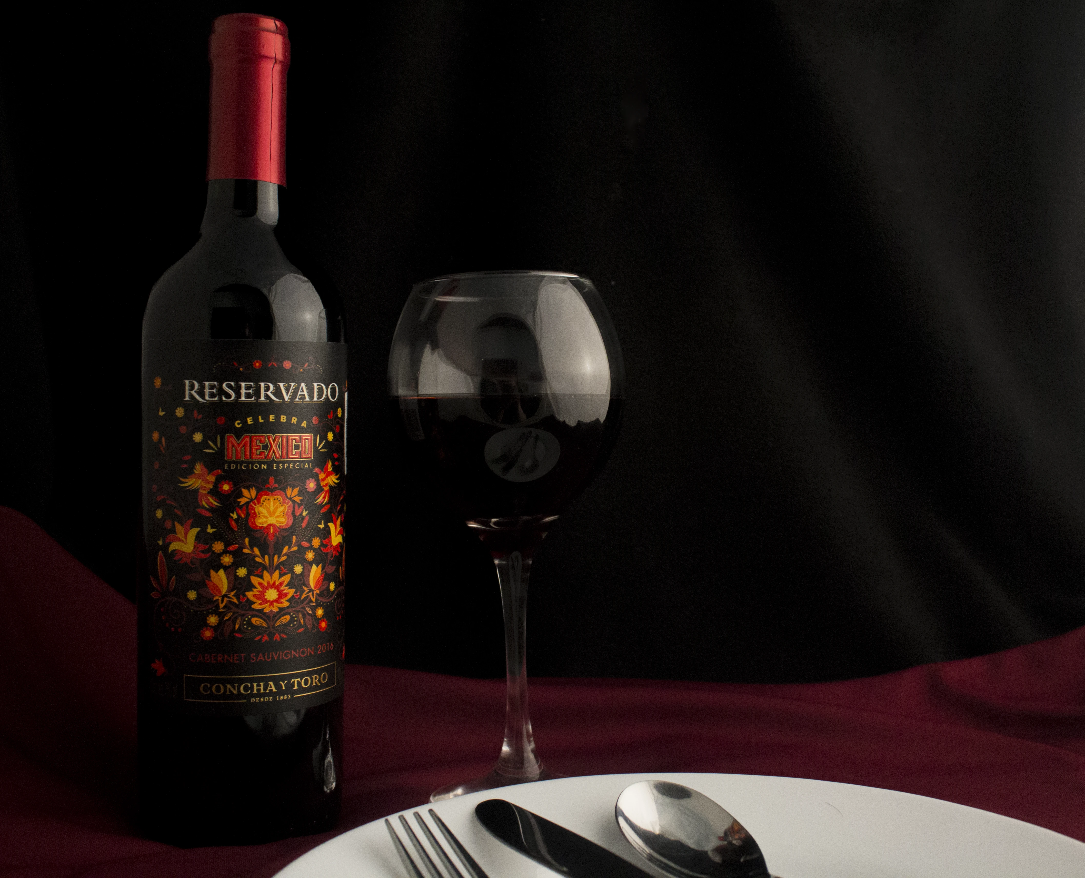 Botella de vino con cubiertos de mesa en escenario para fotografía de producto.