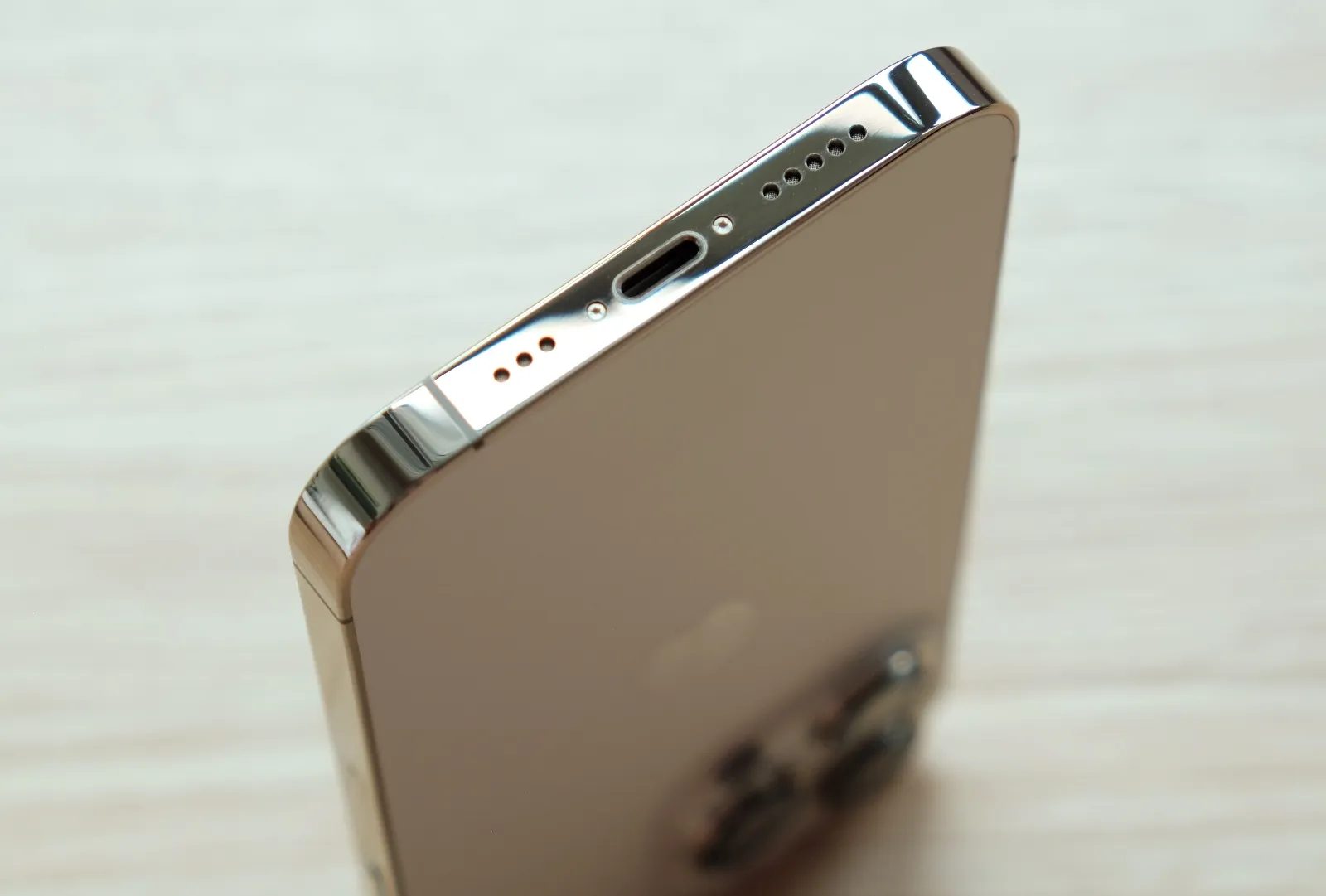 the bottom of a gold iphone focusing on the speakers and charging port