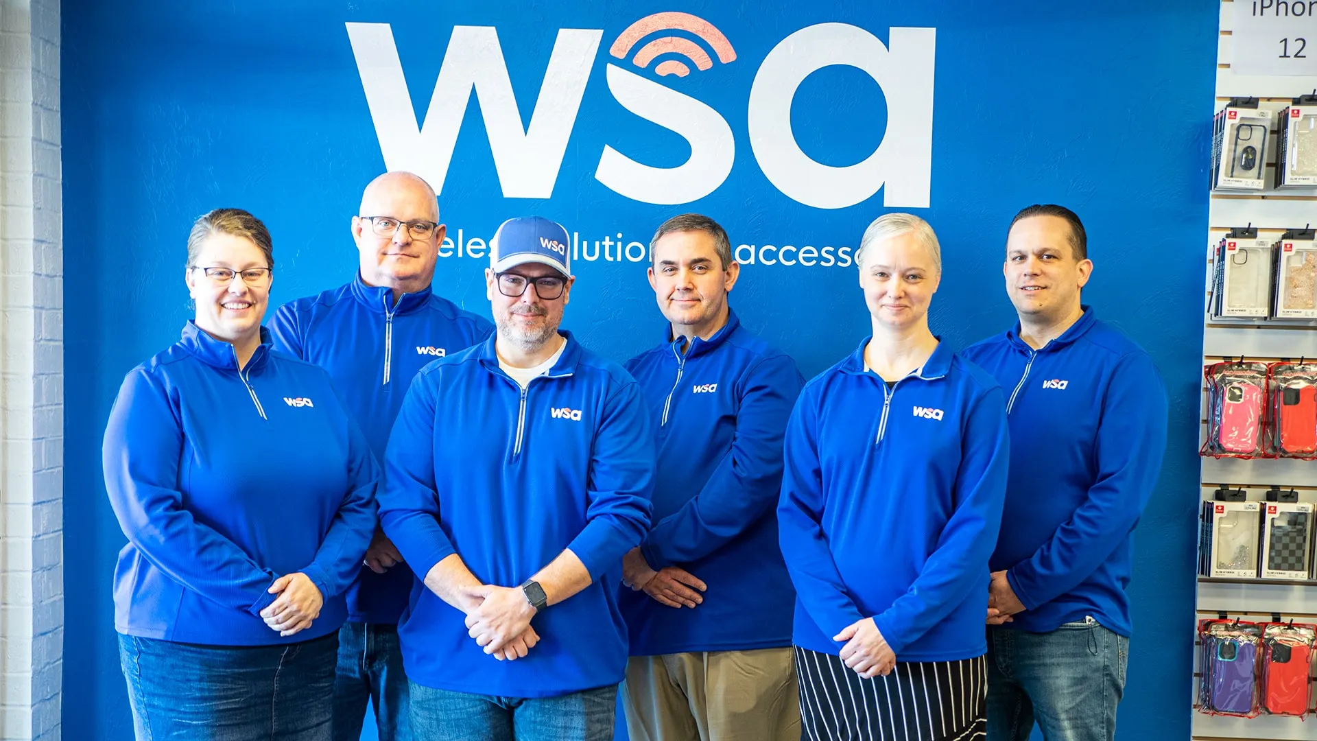 The WSA team standing in front of their logo in one of their stores