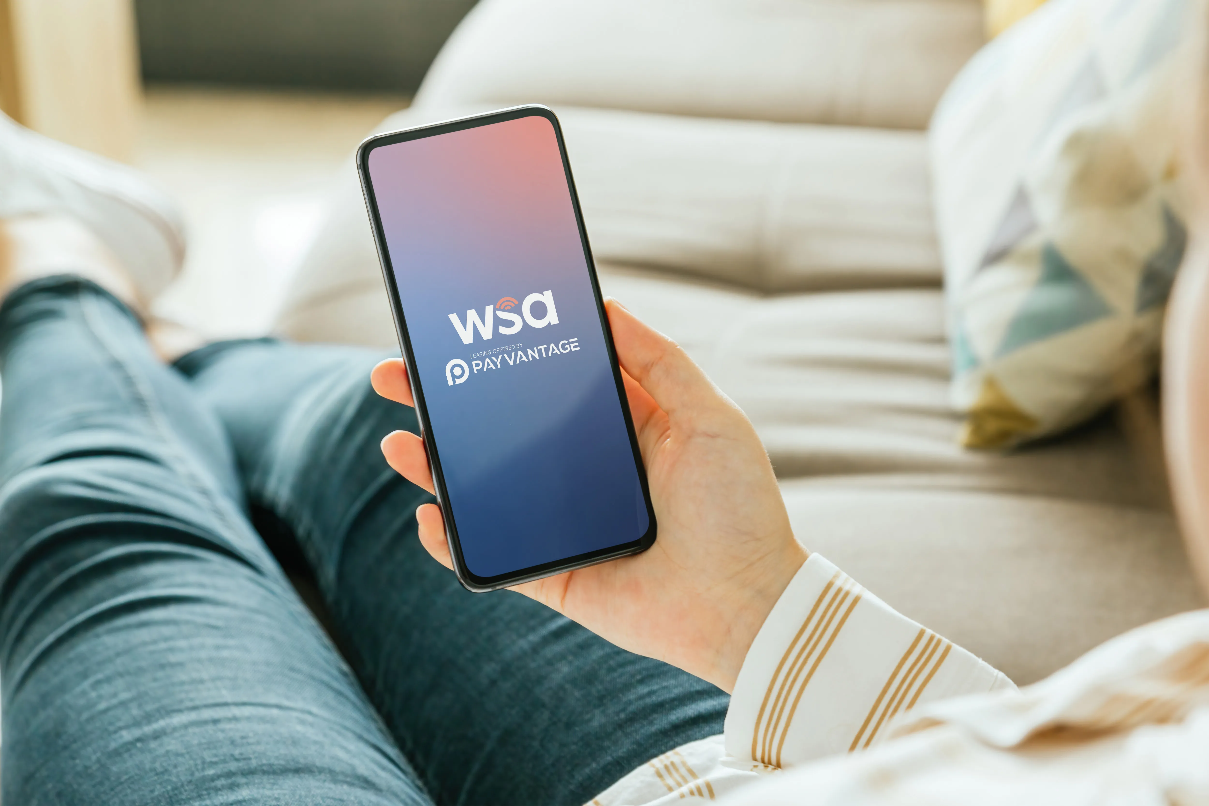 A person laying on a couch looking at a WSA Payvantage page on their phone