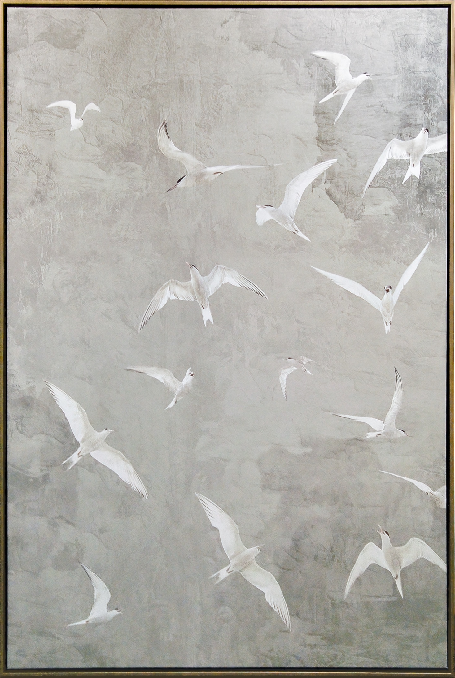 Soft tones of mist gray, pale stone, and muted ivory form a gently textured background against which luminous white birds sweep across the composition in varied, graceful motion. The vertical arrangement emphasizes upward movement and openness, while the clean frame presentation gives the piece a refined, contemporary presence suited to calm, light-filled interiors.
